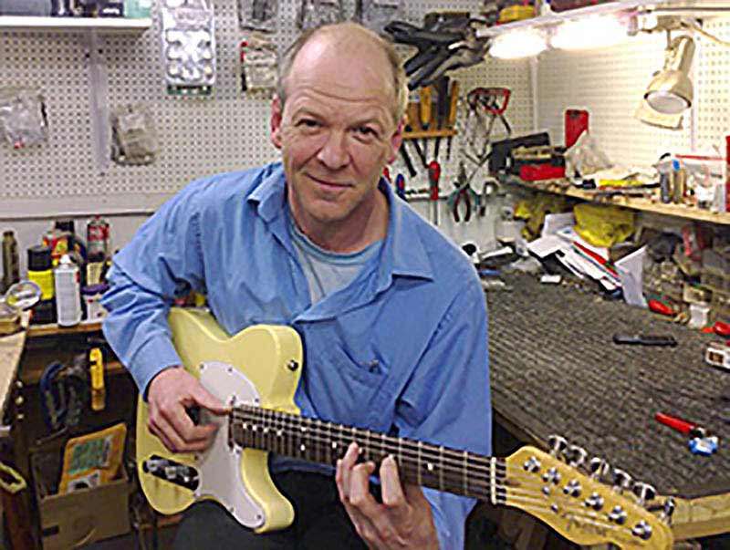 Playing guitar in his workshop.