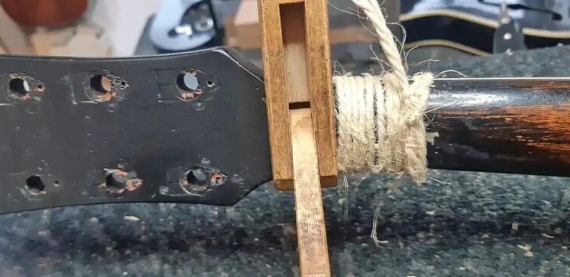 Headstock Repair Clamping Process Close-up of a Gibson Les Paul guitar headstock clamped with a custom wooden luthier jig and wrapped with twine during a neck break repair at Tim Marten Repairs.