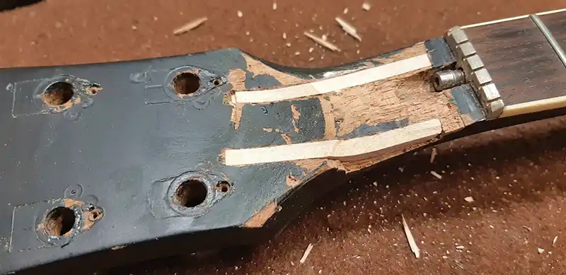 Neck Splint Shaping and Sanding Repair Close-up of a Gibson Les Paul guitar neck showing inserted wood splints being hand-carved and flush-sanded level with the headstock and truss rod transition zone at Tim Marten Repairs.