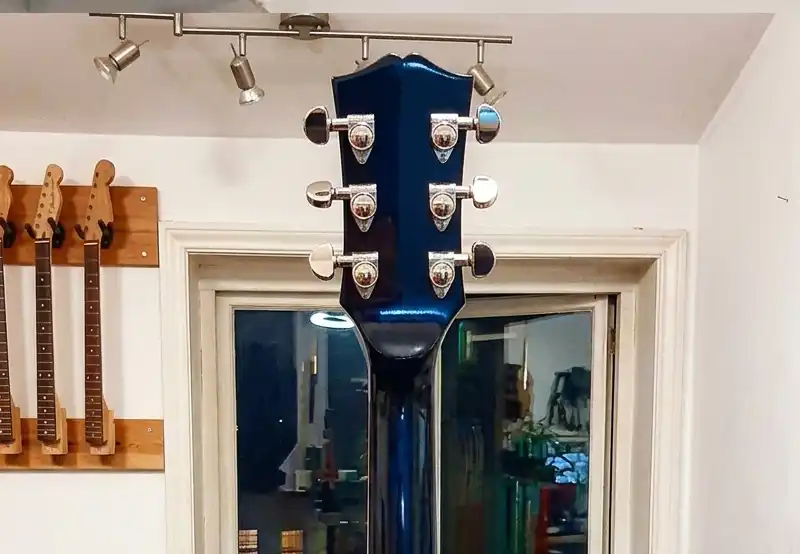 Fully Repaired and Refinished Neck Back view of a metallic blue Gibson Les Paul guitar showing a seamless, fully repaired and refinished headstock joint and neck with reinstalled tuning pegs at Tim Marten Repairs.