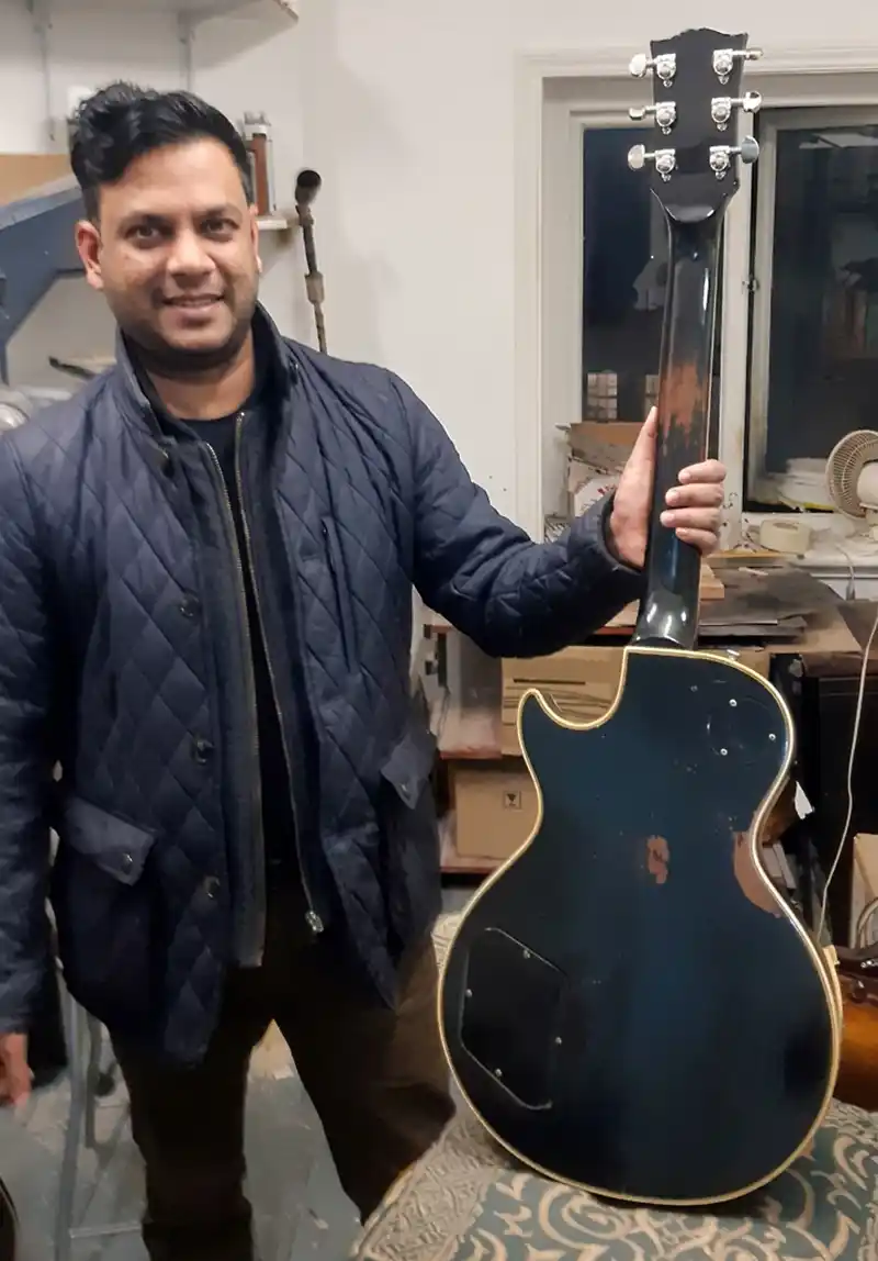 Satisfied Client with Repaired Guitar Smiling customer holding up his restored Gibson Les Paul guitar inside the workshop following a successful neck repair at Tim Marten Repairs.