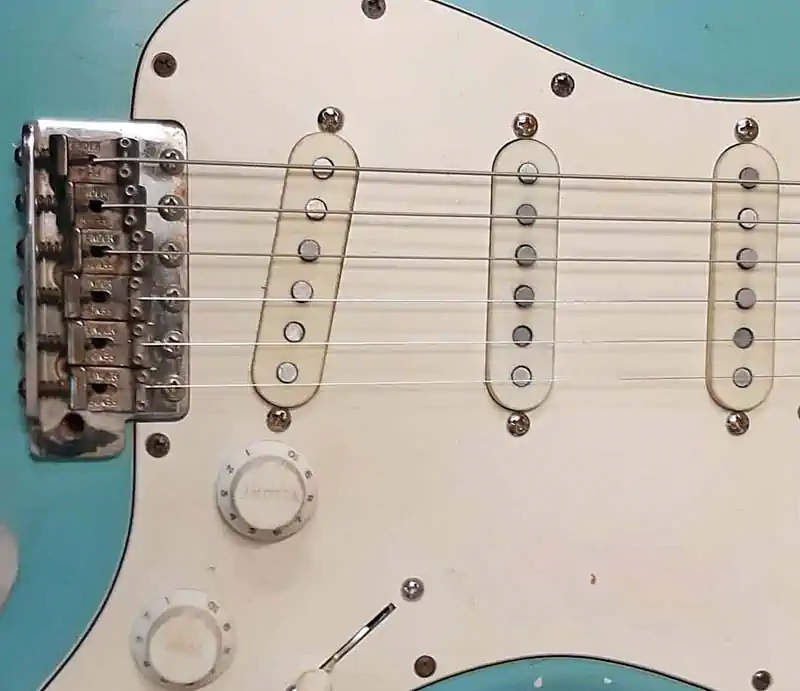 Close-up of a Daphne Blue Tim Marten Stratocaster-style guitar showing three single-coil pickups, pickguard, and bridge.