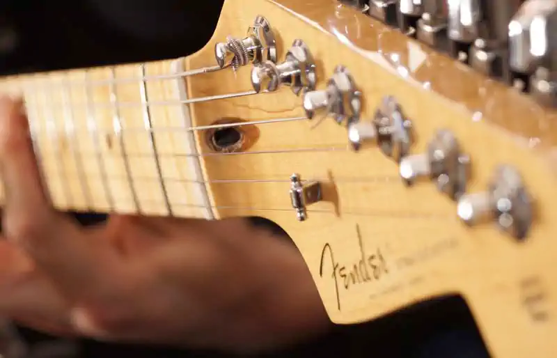 Close-up view of a Fender Stratocaster headstock and maple neck.