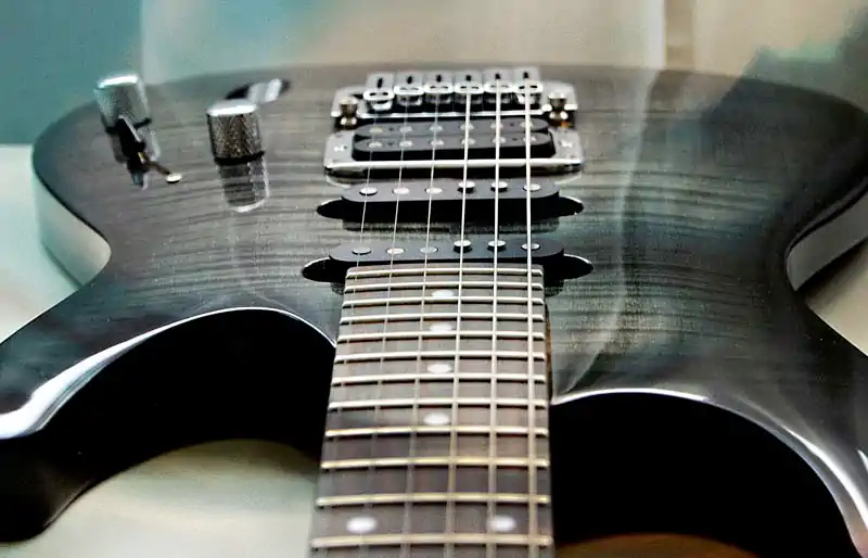 Perspective view along the neck of a dark grey translucent Ibanez electric guitar with HSS pickups and silver knobs.