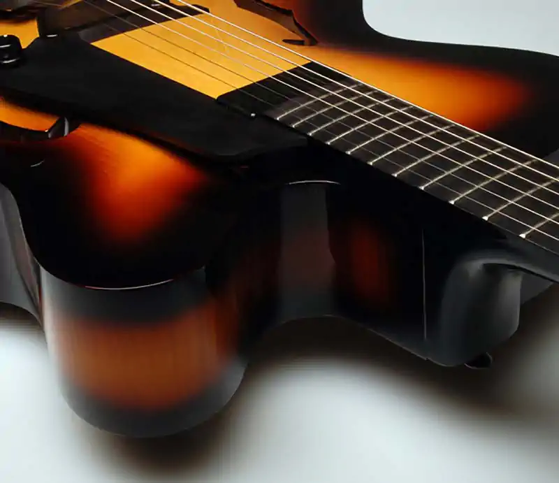 Close-up view of a musician's hand fretting notes on the neck of a sunburst electric bass guitar.