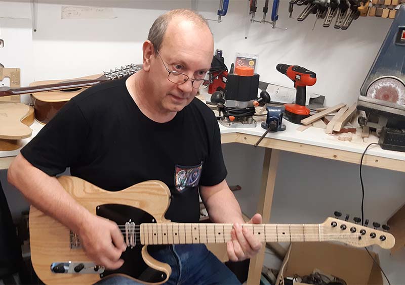 Male musician playing a Tim Marten DoubleTake guitar.