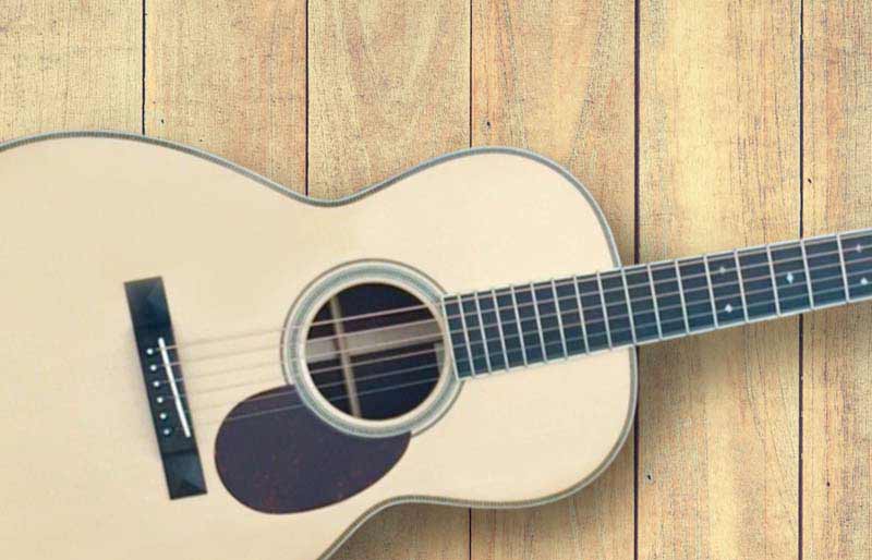 Santa Cruz Guitar Close up of body and neck on wood floorboards.